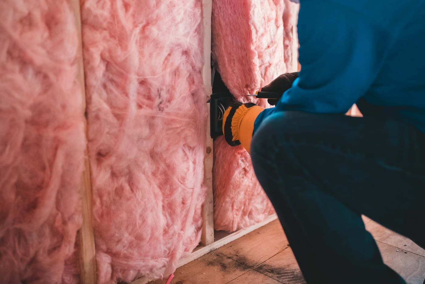 Un artisan gantés pose de l’isolant entre les montants d’un mur